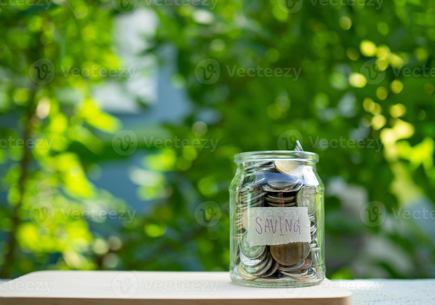 Piggy bank bottle with saving sign on natural bokeh background photo