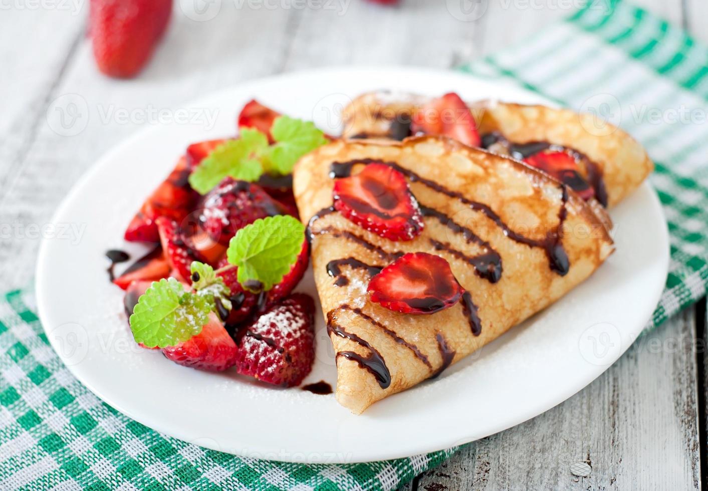 Pancakes with strawberries and chocolate decorated with mint leaf photo