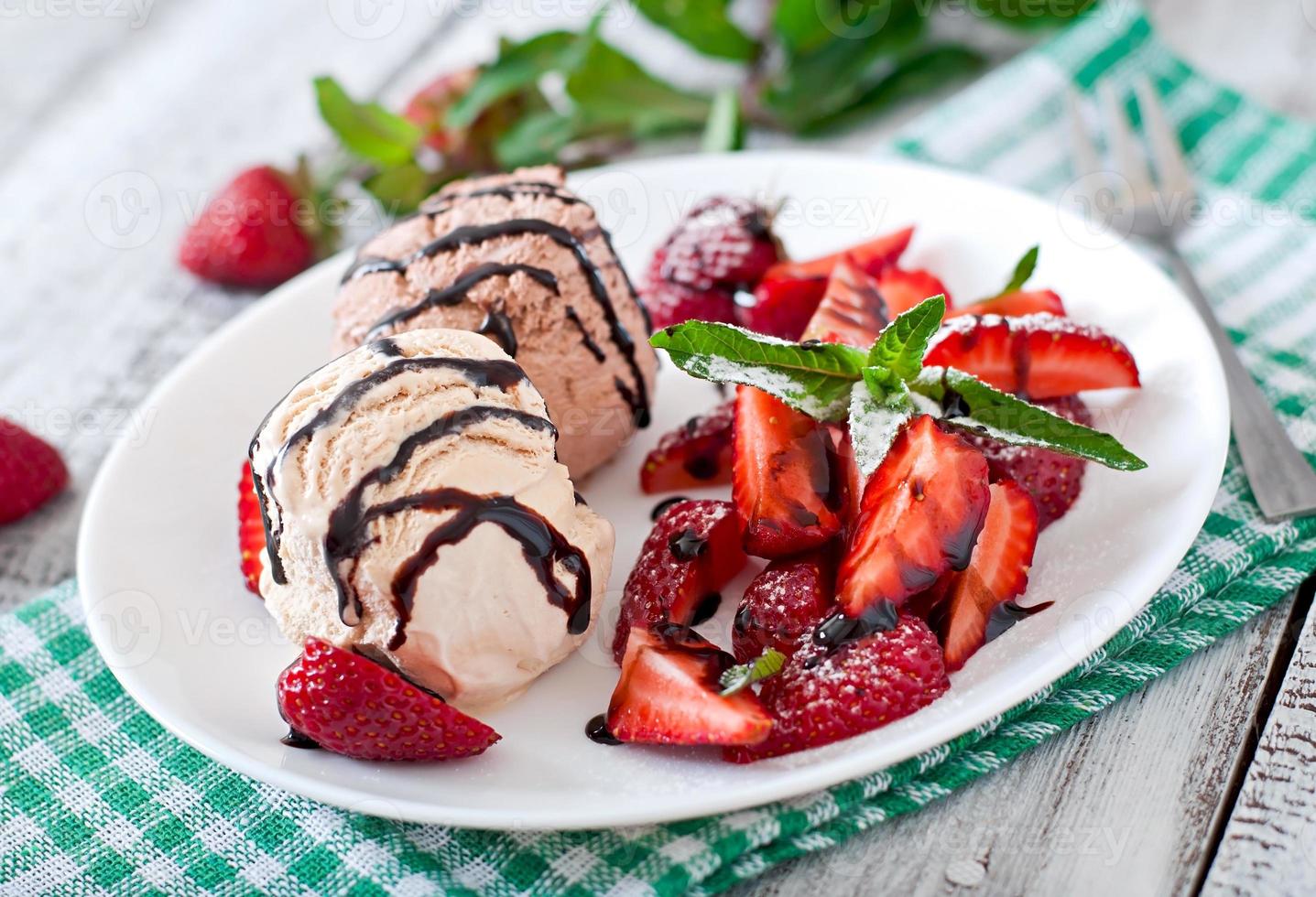 Ice cream with strawberries and chocolate on a white plate photo