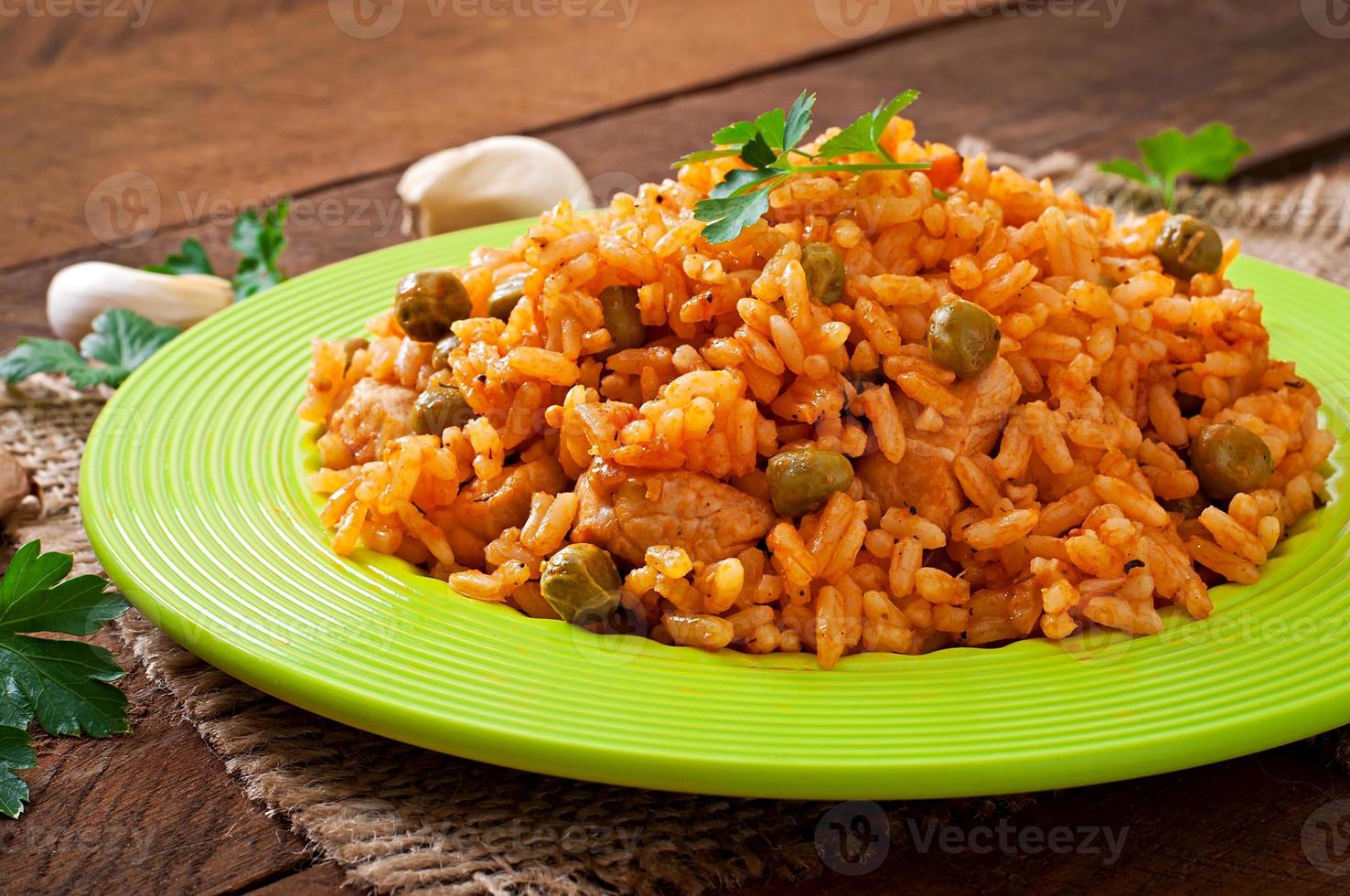 Pilaf with chicken, carrot and green peas on white plate photo