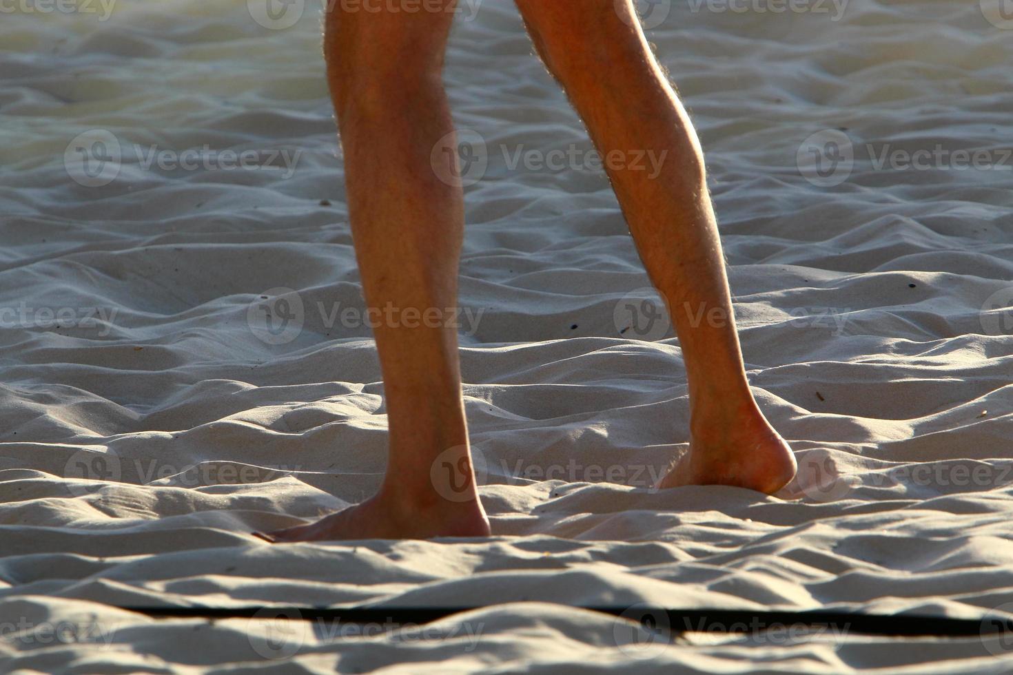 A man walks barefoot on the sand by the sea photo