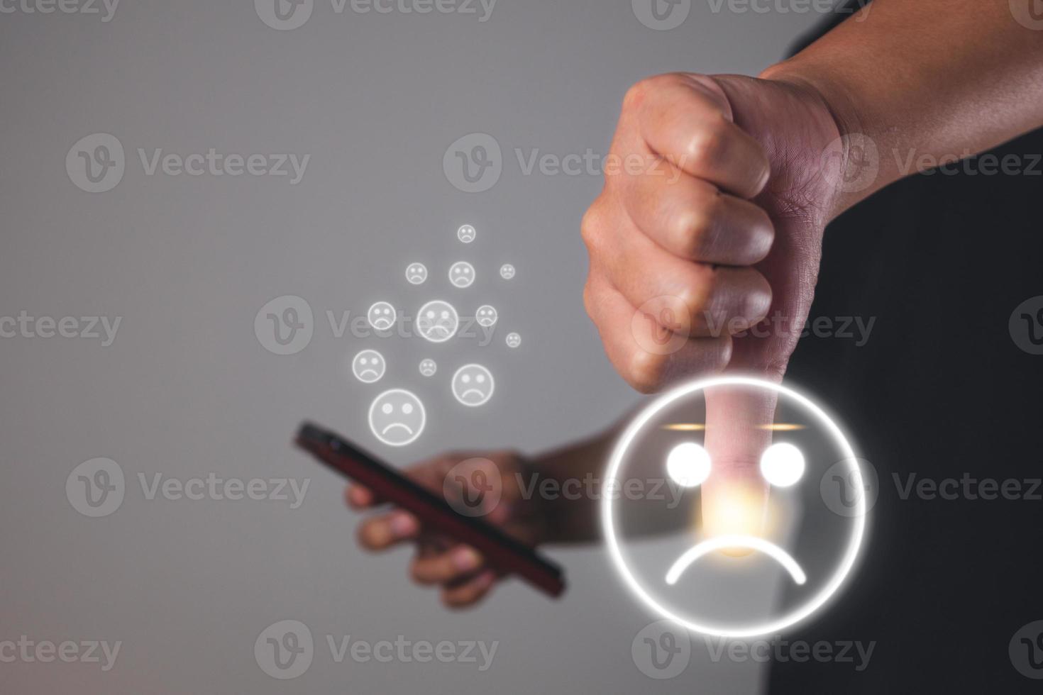 Evaluation and satisfaction concept. Hand shows thumb down with sad emoji face. Medium close up shot. photo