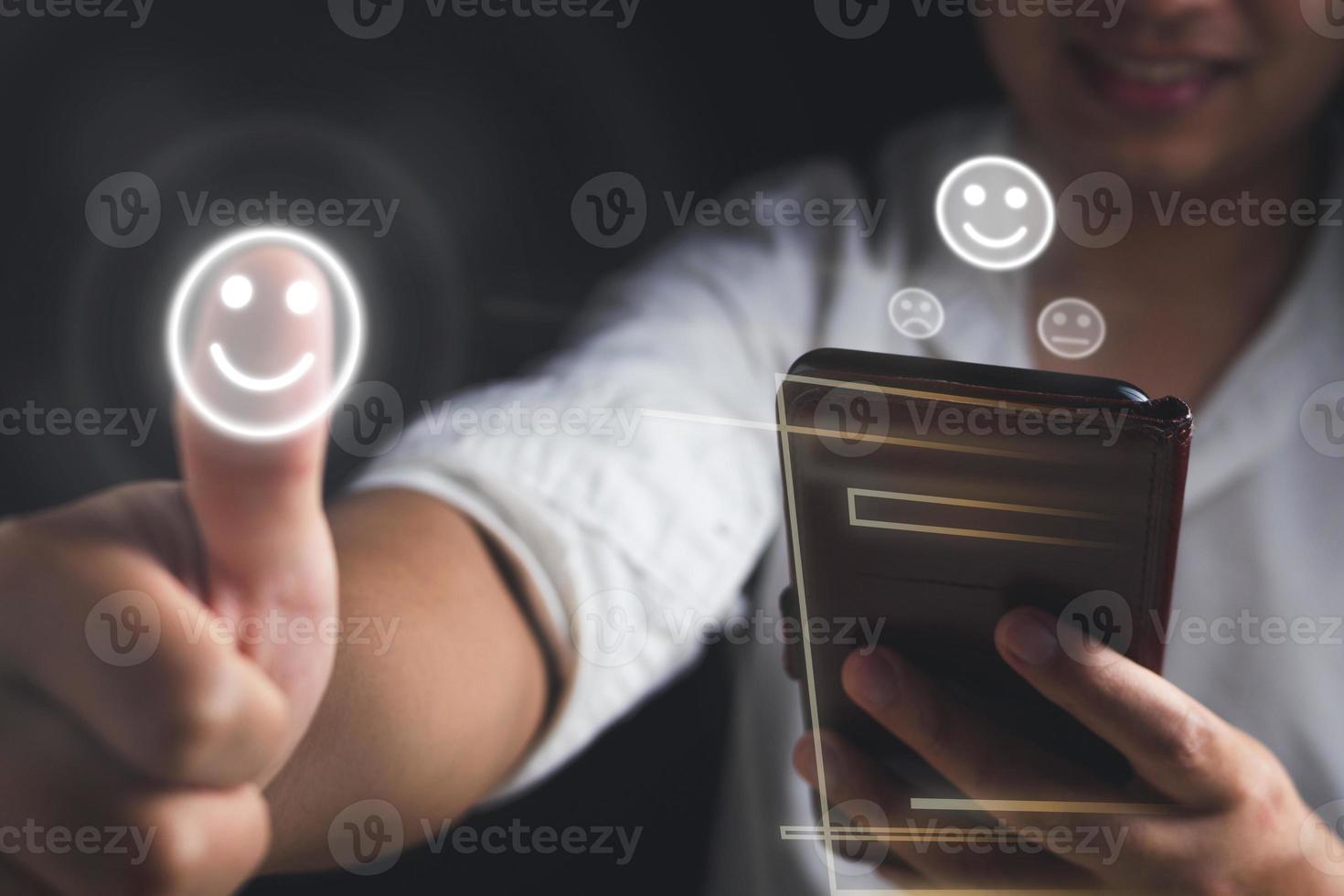 Evaluation and satisfaction concept. The smile man shows a thumps up that is an excellent review with unidentified model of mobile phone. Medium close up shot on black background. photo