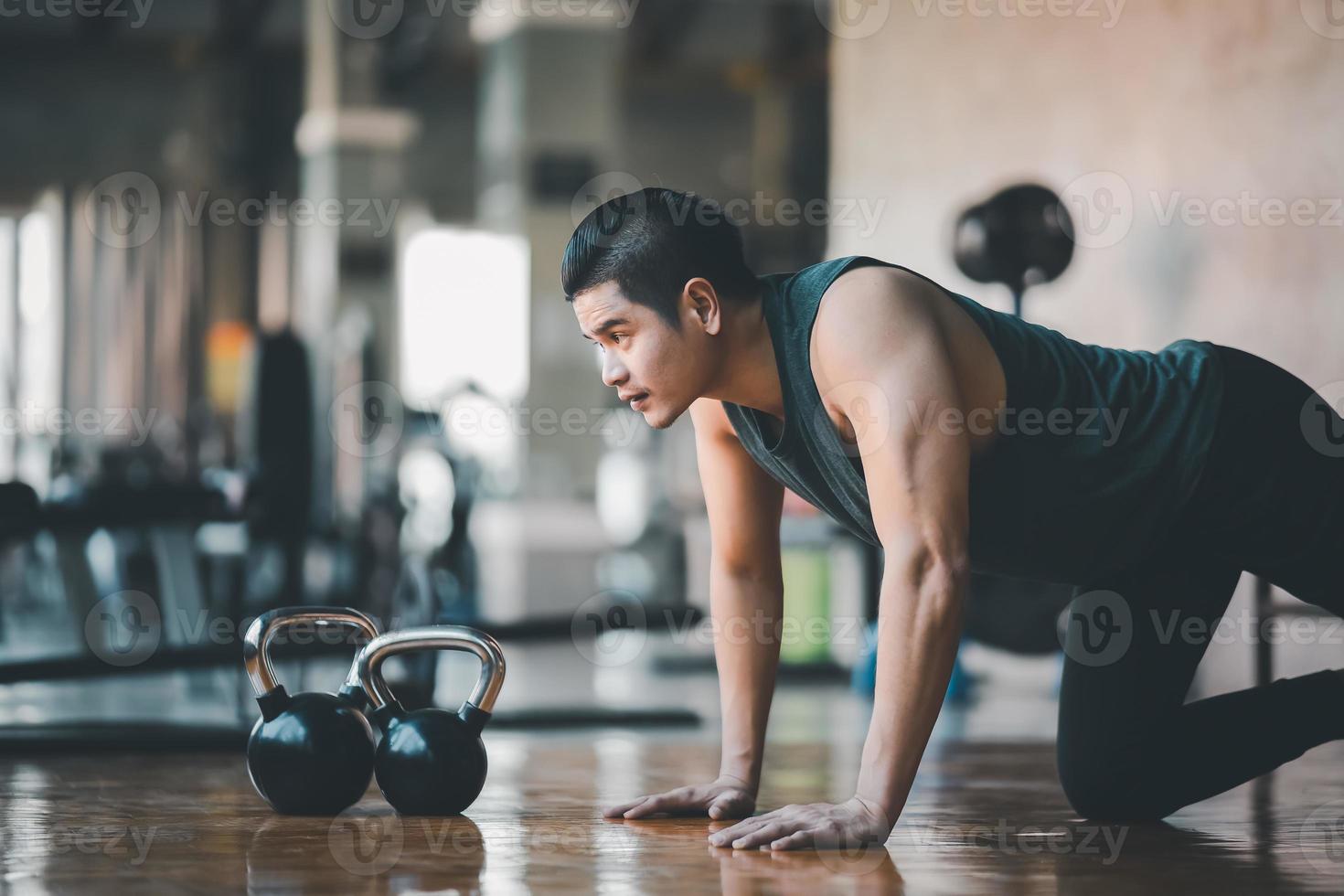 Asian fit sportsman doing push up exercise on the wood floor at the gym fitness. Sport man exercise at the sport center. Sport fitness gym concept. photo