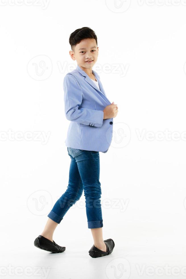 niño asiático de 10 años con un blazer informal caminando inteligente y felizmente mirando la cámara con un fondo blanco aislado foto