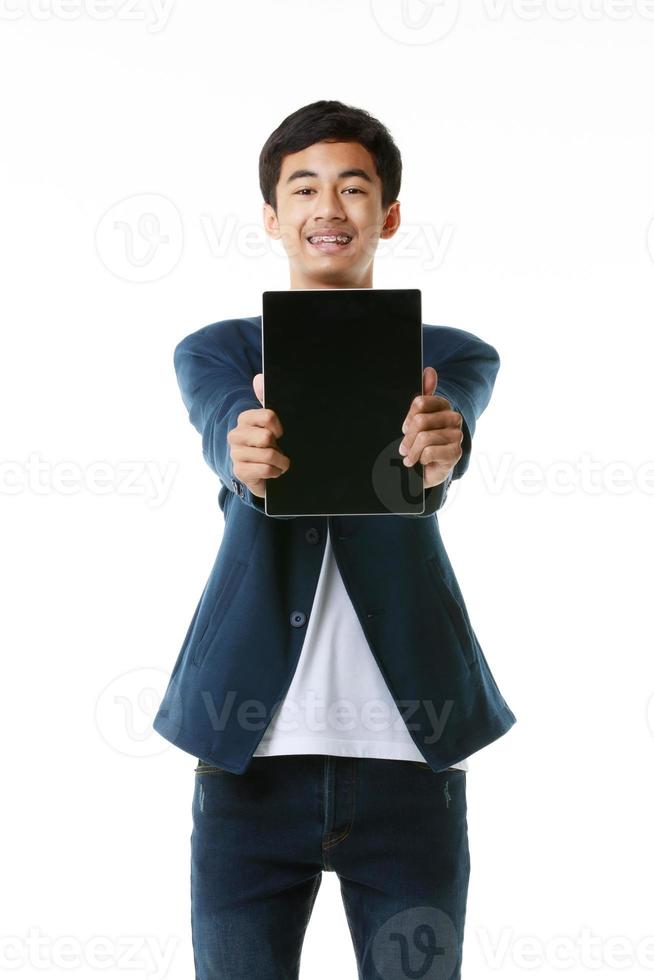 estudiante asiático de secundaria de 15 años sosteniendo y mostrando una pantalla en blanco de una tableta. concepto y tecnología de la vida adolescente moderna. foto