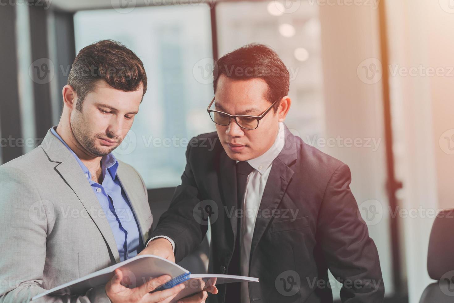 dos hombres de negocios hablando con un compañero de raza mixta asiático y caucásico, jefe ejecutivo que trabaja ayudando a cuidar a un empleado en el cargo. foto