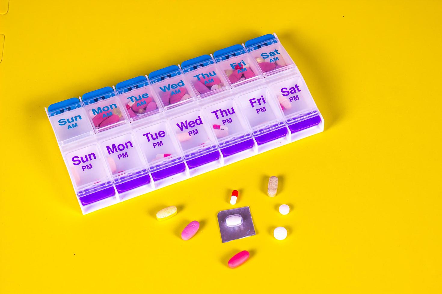 Weekly Pill Box Container On Smooth Yellow Background photo