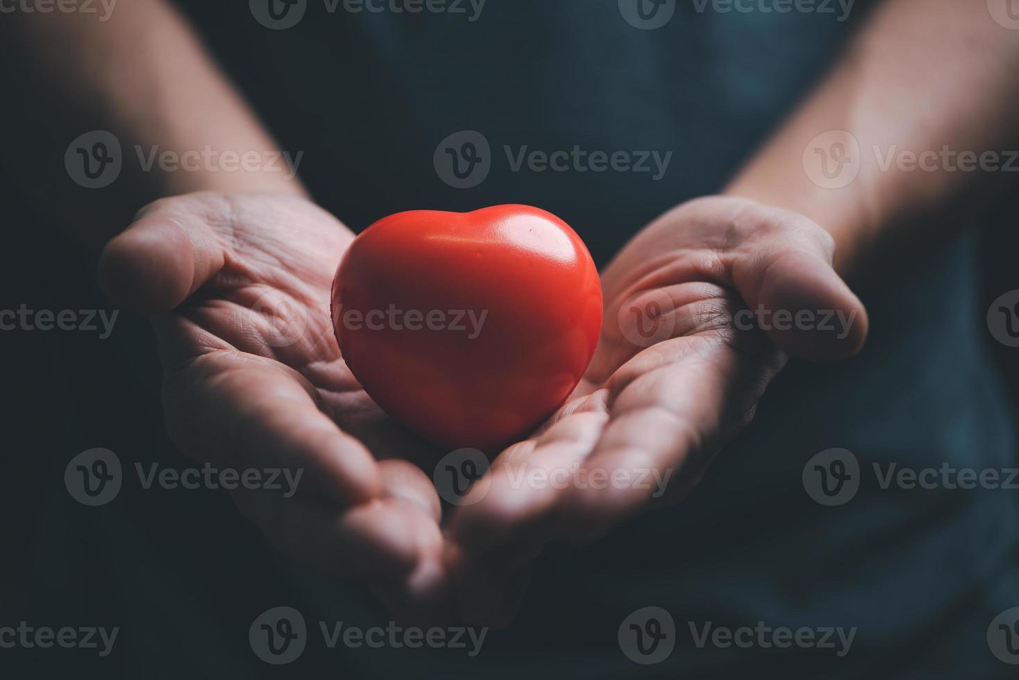 Hands holding and giving red heart for love, health care, organ donation, world heart day, world health day, mindfulness, well being, family insurance concept. photo