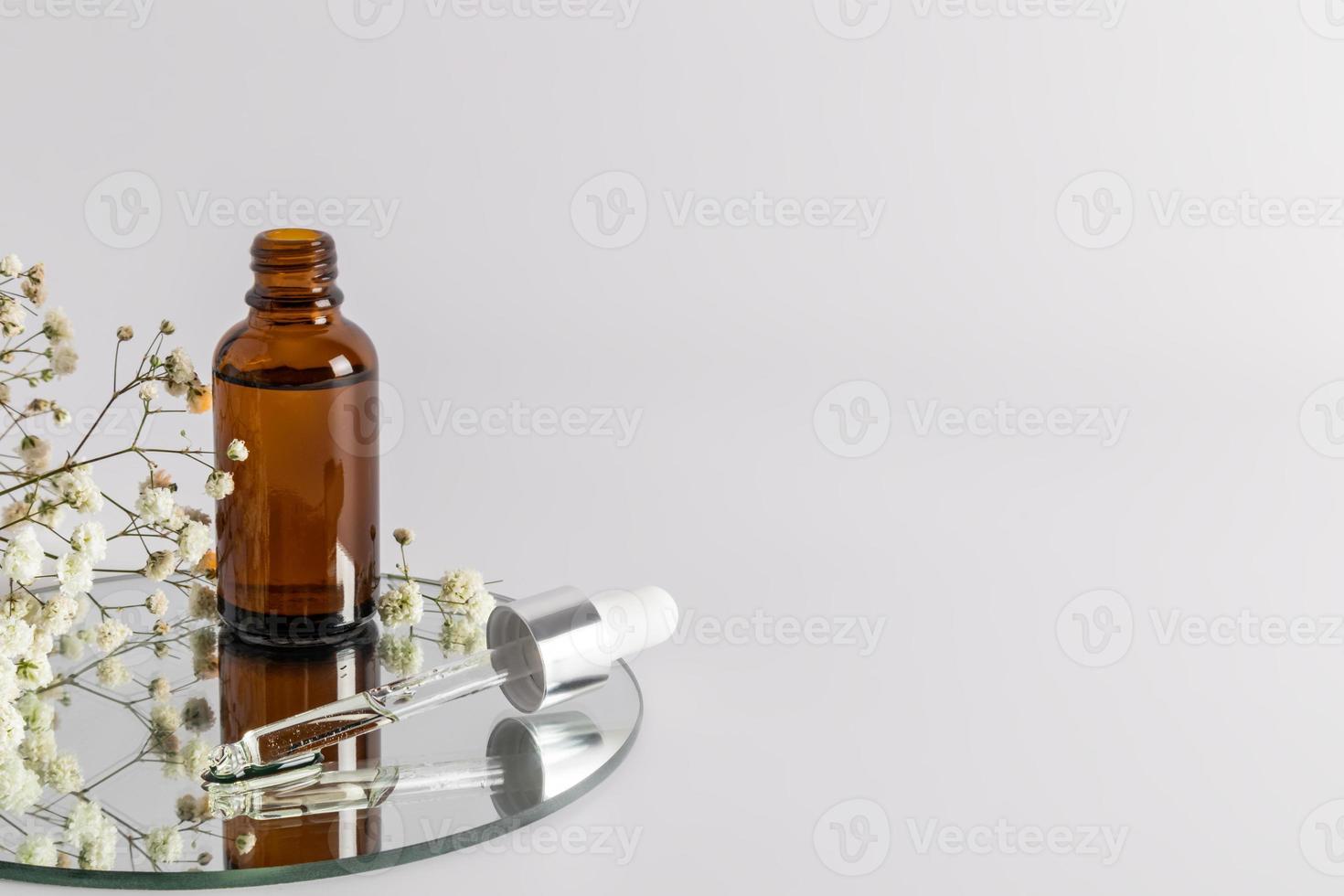an open bottle with a moisturizer and skin nourishing agent stands on a round mirror with a filled pipette. a copy of the space. selective focus. photo