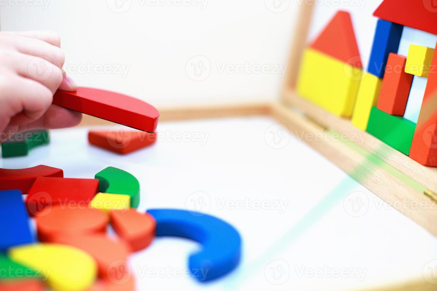 el niño juega un juego educativo magnético de madera. niño juega con un juguete sobre un fondo blanco. foto