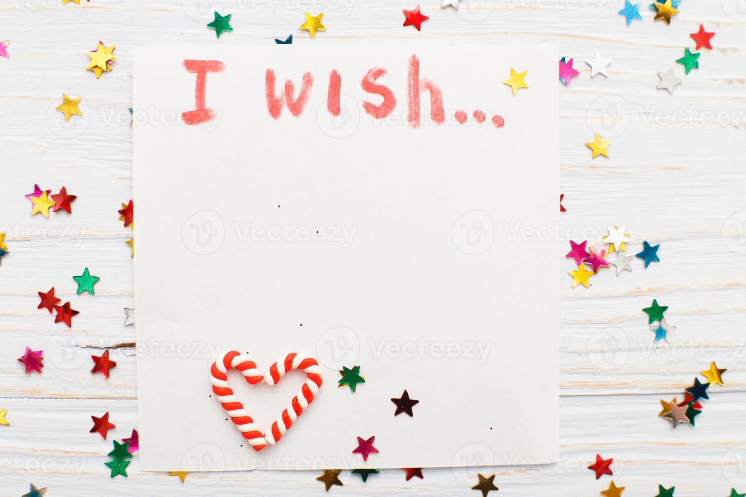 notebook with wish list on vintage wooden table with candy canes. christmas planning concept. photo