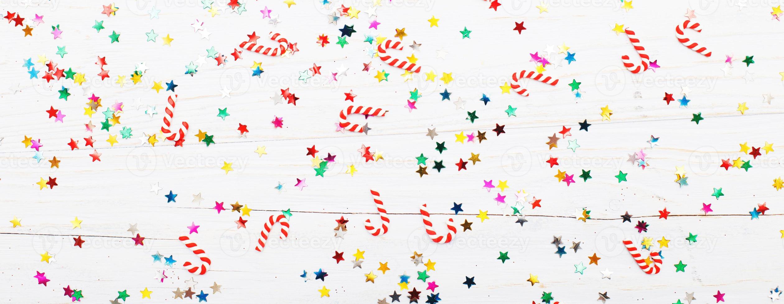 Christmas background with candy canes and multicolored sequins on blue wooden background photo