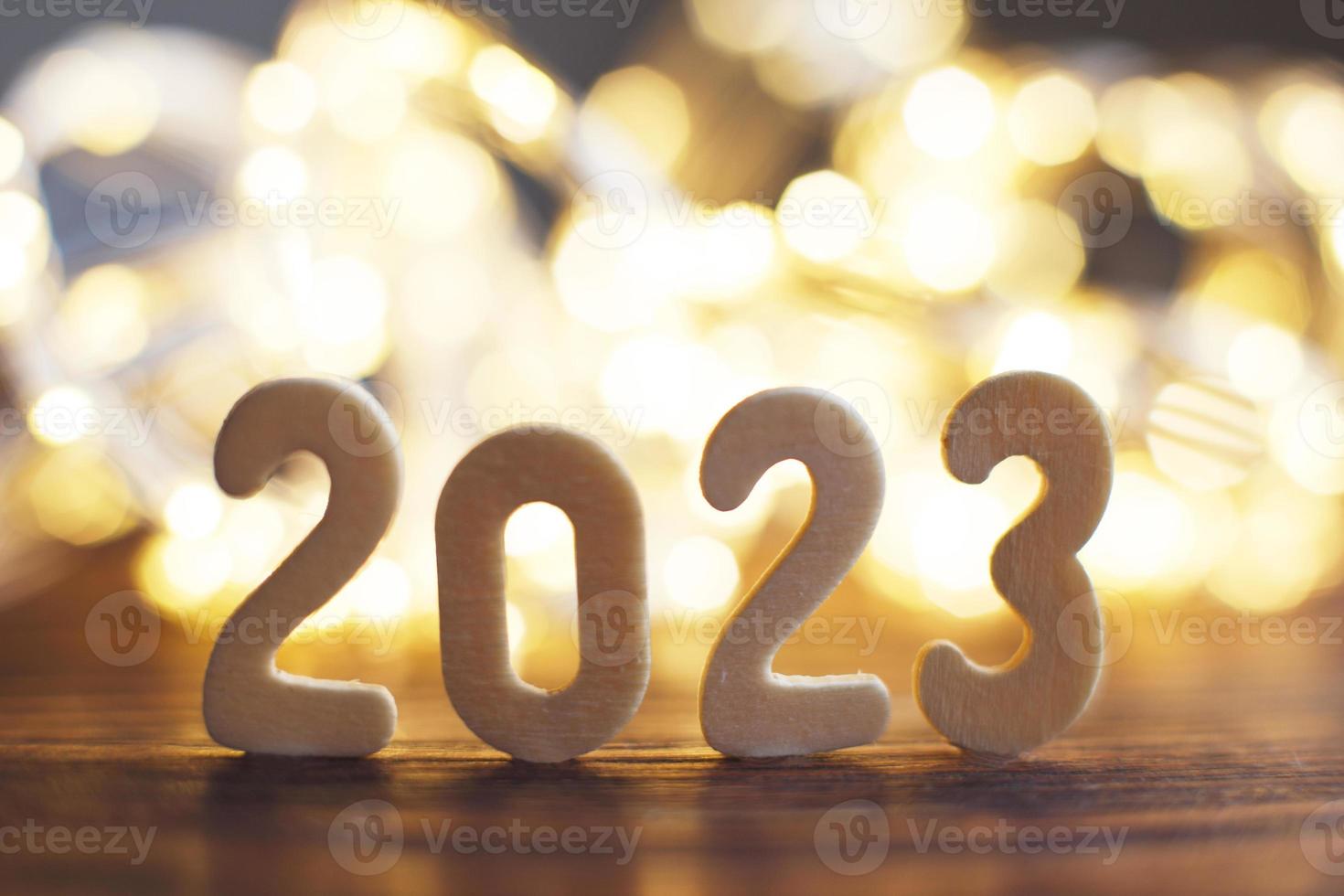 wooden number 2023 onchristmas beautifull shiny gold background. sparkle festive blurred bokeh photo