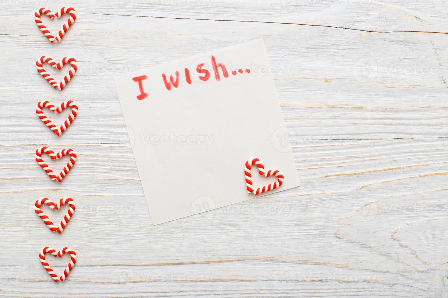 notebook with wish list on vintage wooden table with candy canes. christmas planning concept. photo