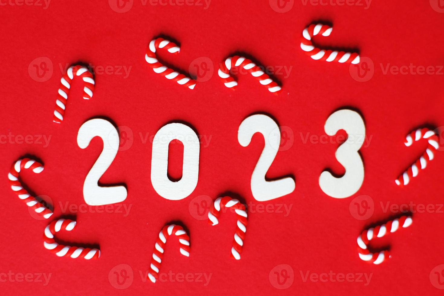 Christmas composition with candy canes and number 2023 on a red background. Copy space for text photo