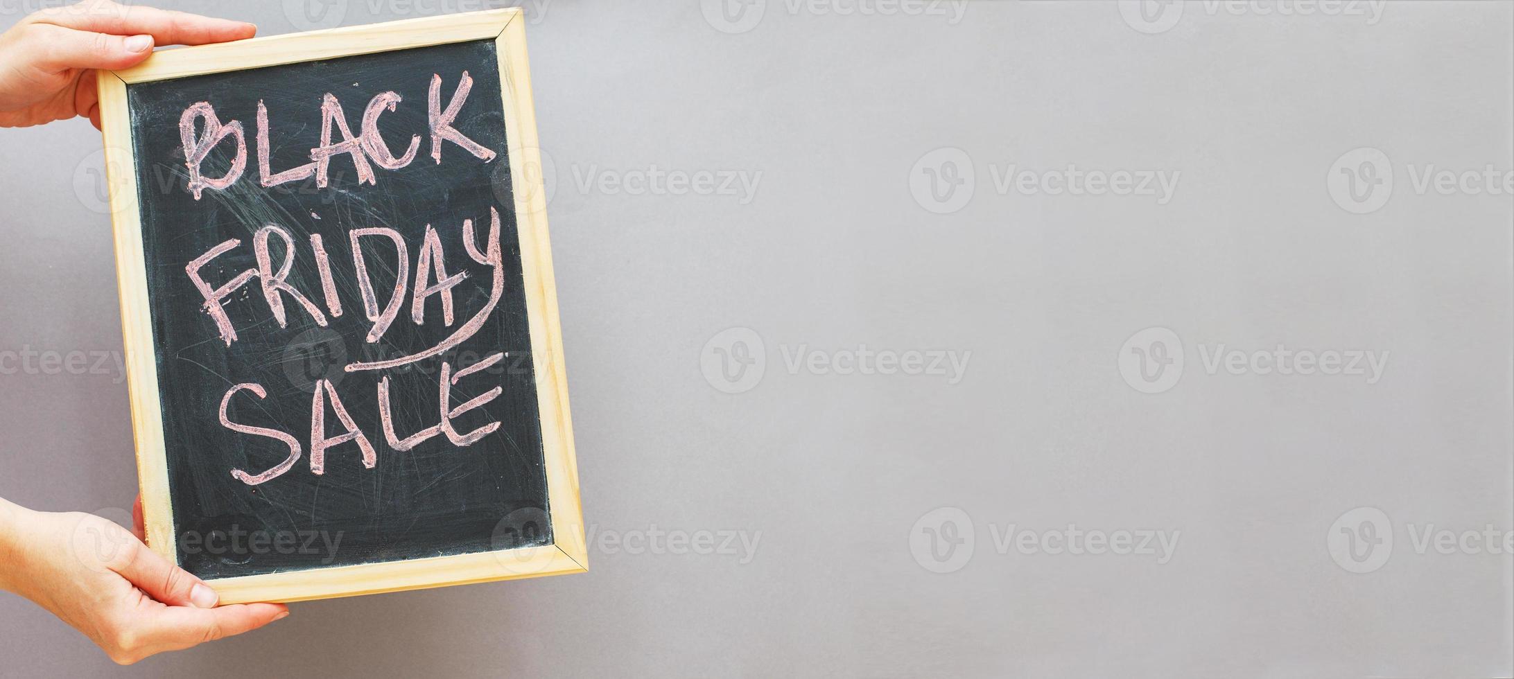 woman hands holding black friday sale announcement on grey background. banner photo