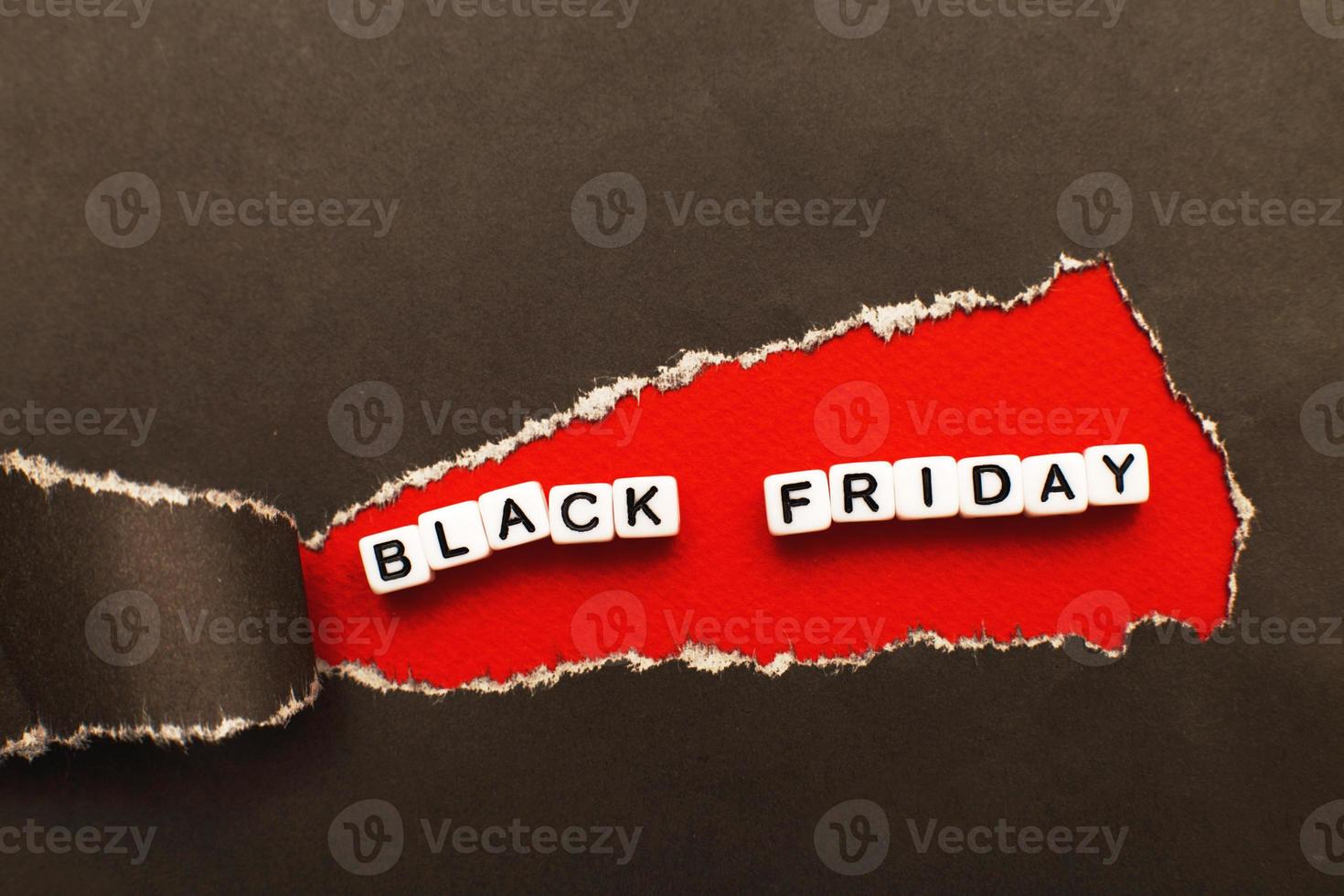 curl of torn black paper on red background. advertising and black friday sale concept. photo