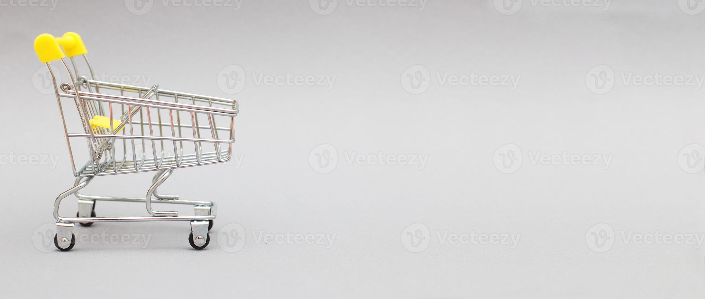 The metal shopping cart on a grey background. banner photo