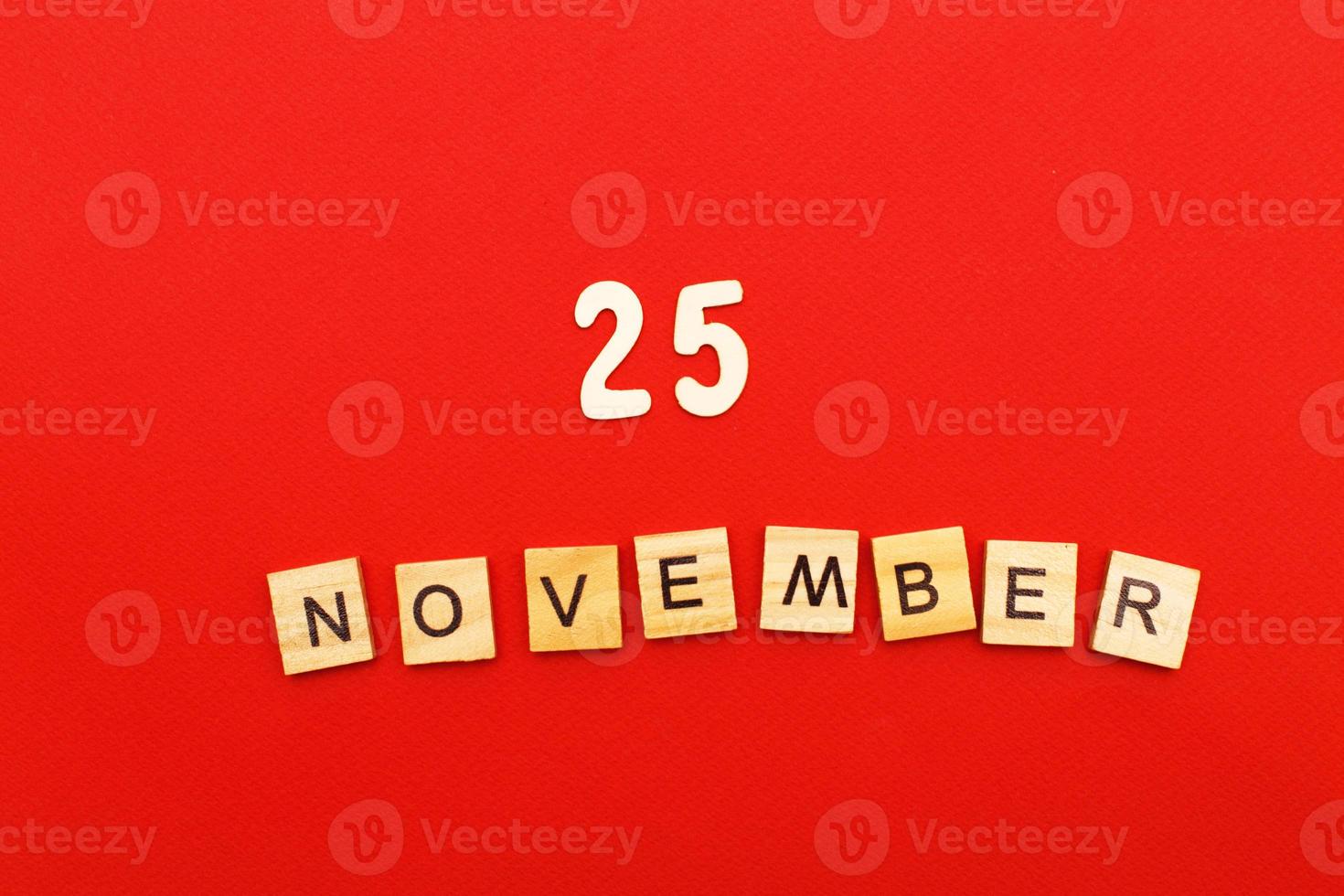 inscription November 25 made by wooden cubes on a red background. photo