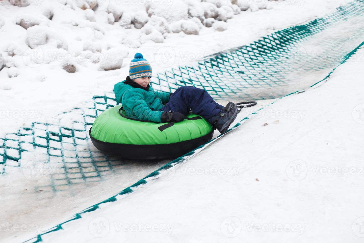 Child having fun on snow tube. Boy is riding a tubing. Winter entertainment. kid sliding downhill on tube photo