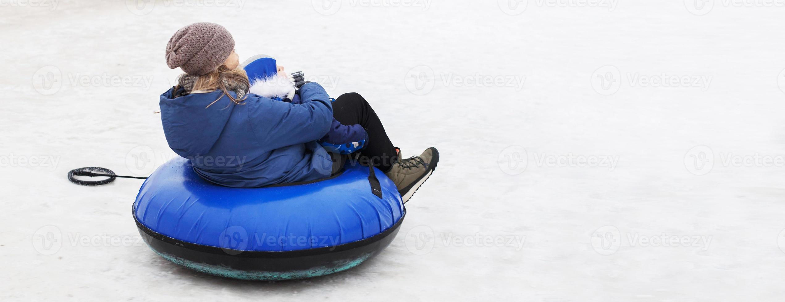 Family having fun on snow tube. mother with kid is riding a tubing. people sliding downhill on tube. banner photo