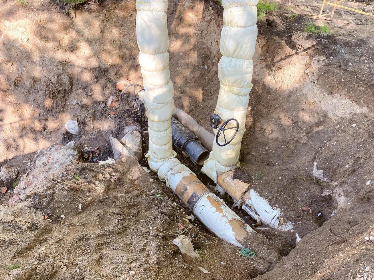 laying of underground communications for residential buildings. plumbing pipes in black with a huge white valve to regulate the flow of water photo