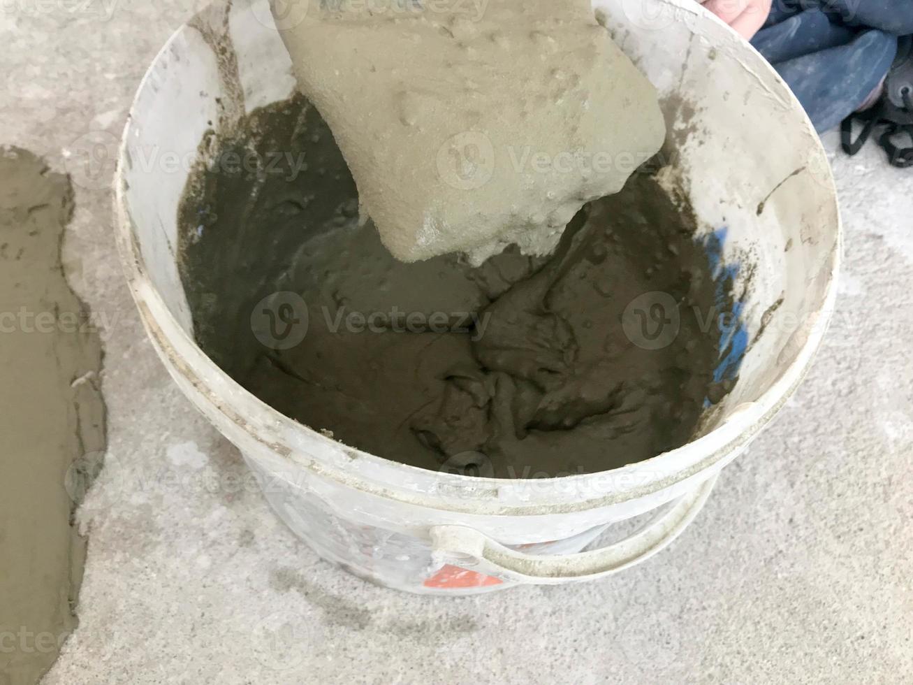 Large white plastic construction bucket with spatula and plaster, tiled glue, cement for the repair of an apartment, house, leveling the walls and pouring screed on the floor photo