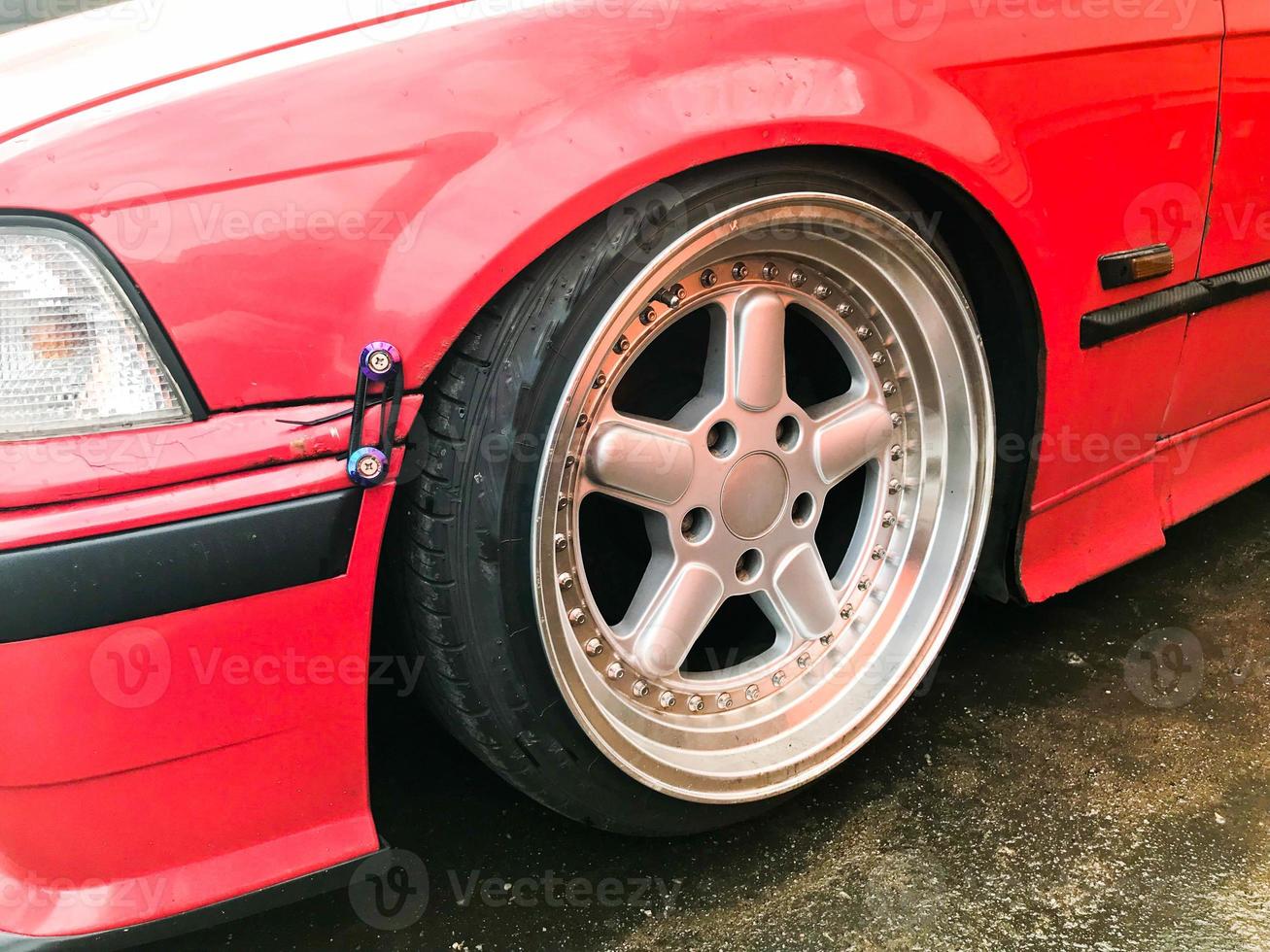 Beautiful big racing wheels of a sports red car with a very low ground clearance on cast shiny expensive alloy wheels in the style of Stans. Tuning cars photo