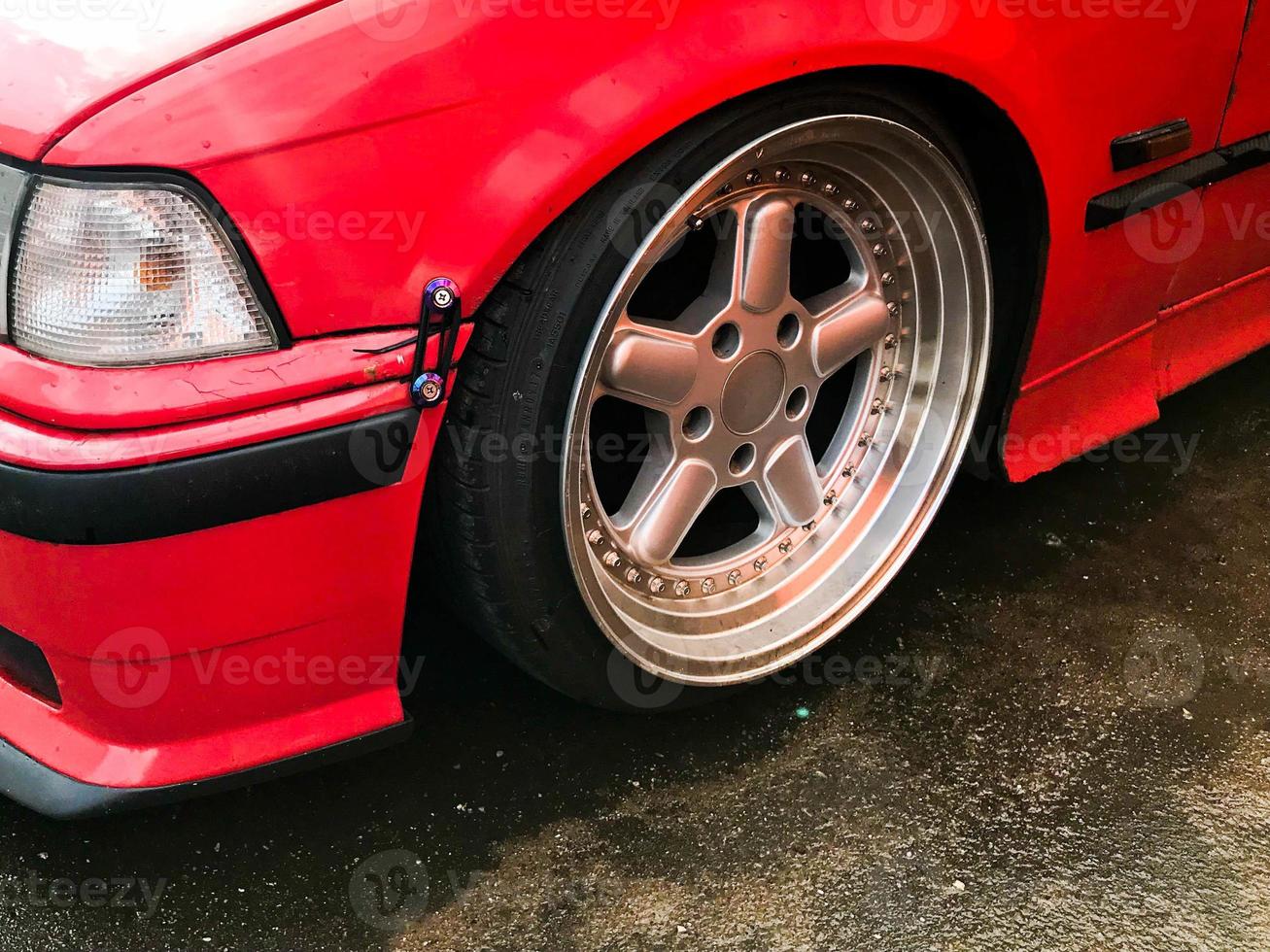 Beautiful big racing wheels of a sports red car with a very low ground clearance on cast shiny expensive alloy wheels in the style of Stans. Tuning cars photo