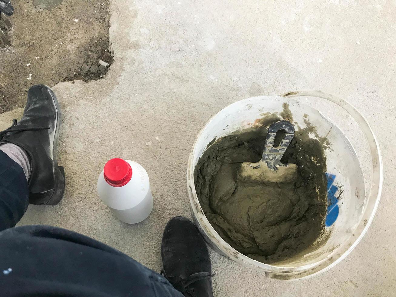 Large white plastic construction bucket with spatula and plaster, tiled glue, cement for the repair of an apartment, house, leveling the walls and pouring photo