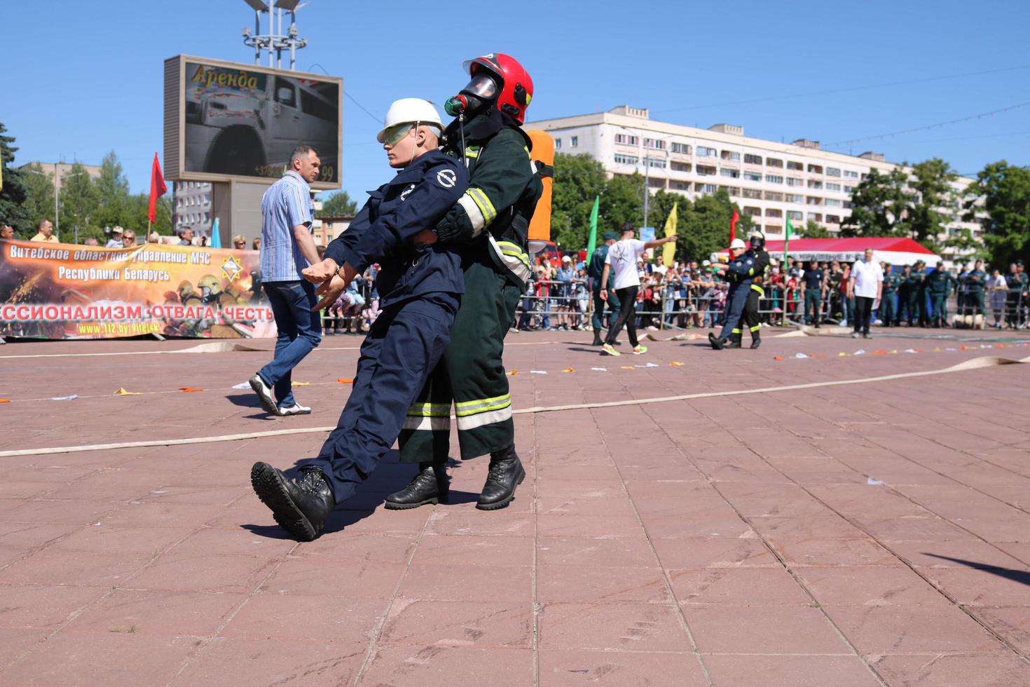 Men firefighter in fireproof suit and helmet rescues drags pulls maniken of worker's man out of danger at exercises, at fire-fighting competitions, Minsk, Belarus, 06.06.2018 photo