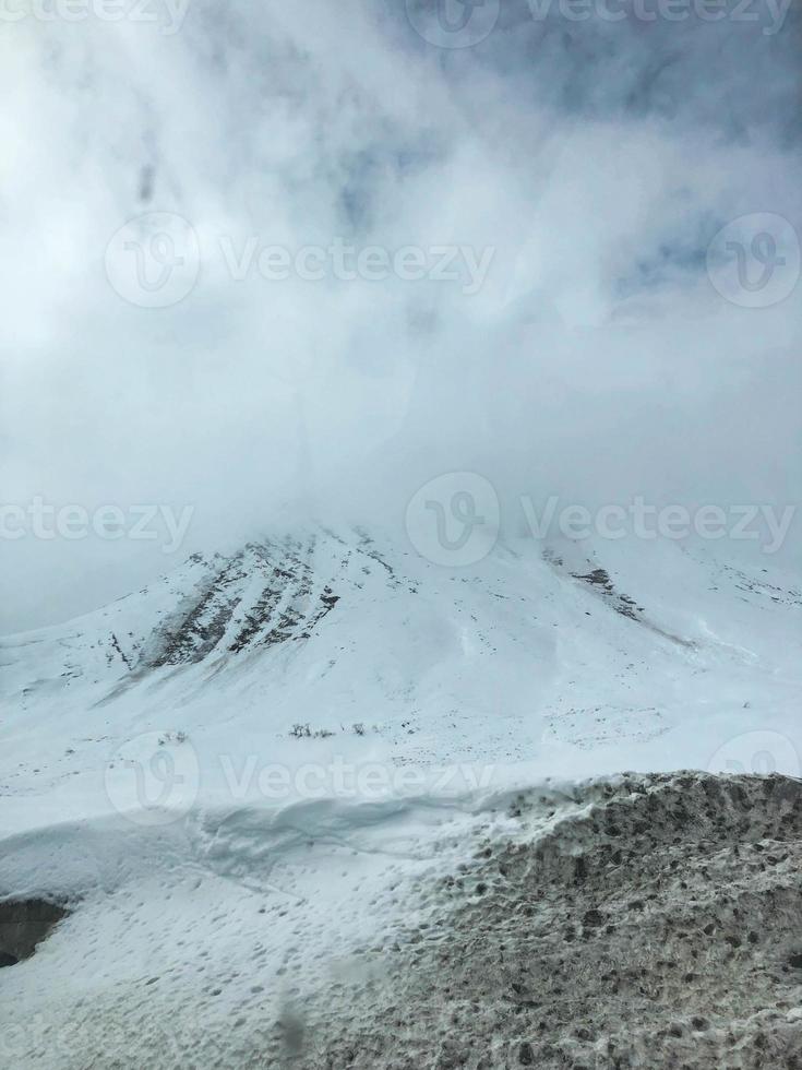 Beautiful mountain cold winter resort landscapes with high mountain peaks mist and snow covered rocks for snowboarding and skiing against a blue sky photo