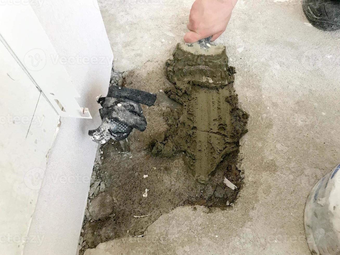Builder hands with a metal spatula plaster the wall, pours the screed with plaster, tile glue, cement for the repair of the apartment, building a house, leveling the walls and pouring t photo