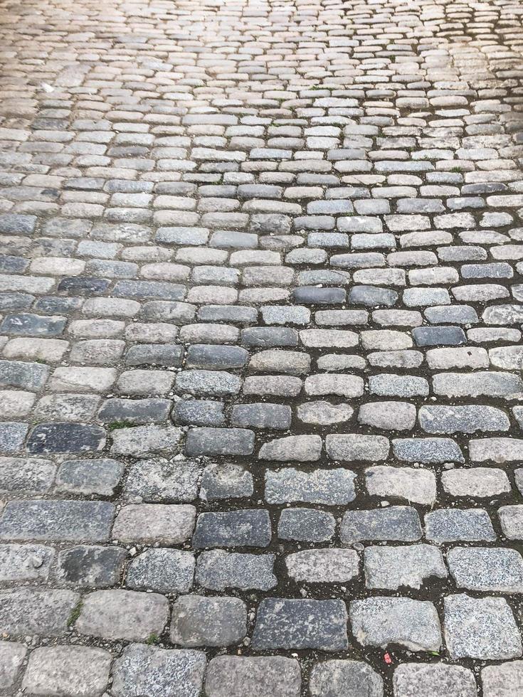 The texture of the old pedestrian stone-paved stone brick gray road with seams. The background photo