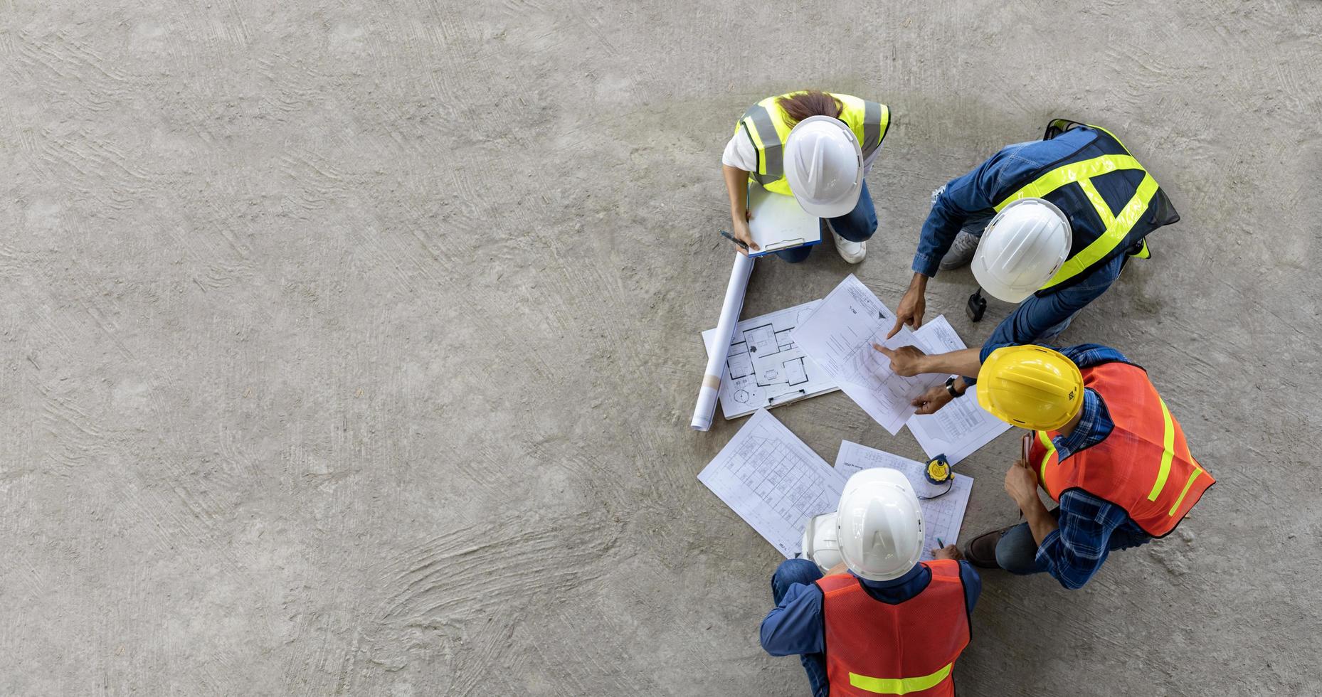 vista superior de la reunión de ingenieros, arquitectos, contratistas y capataces en el sitio de construcción con plano de planta para la industria de proyectos de desarrollo inmobiliario y el concepto de línea de tiempo de vivienda foto