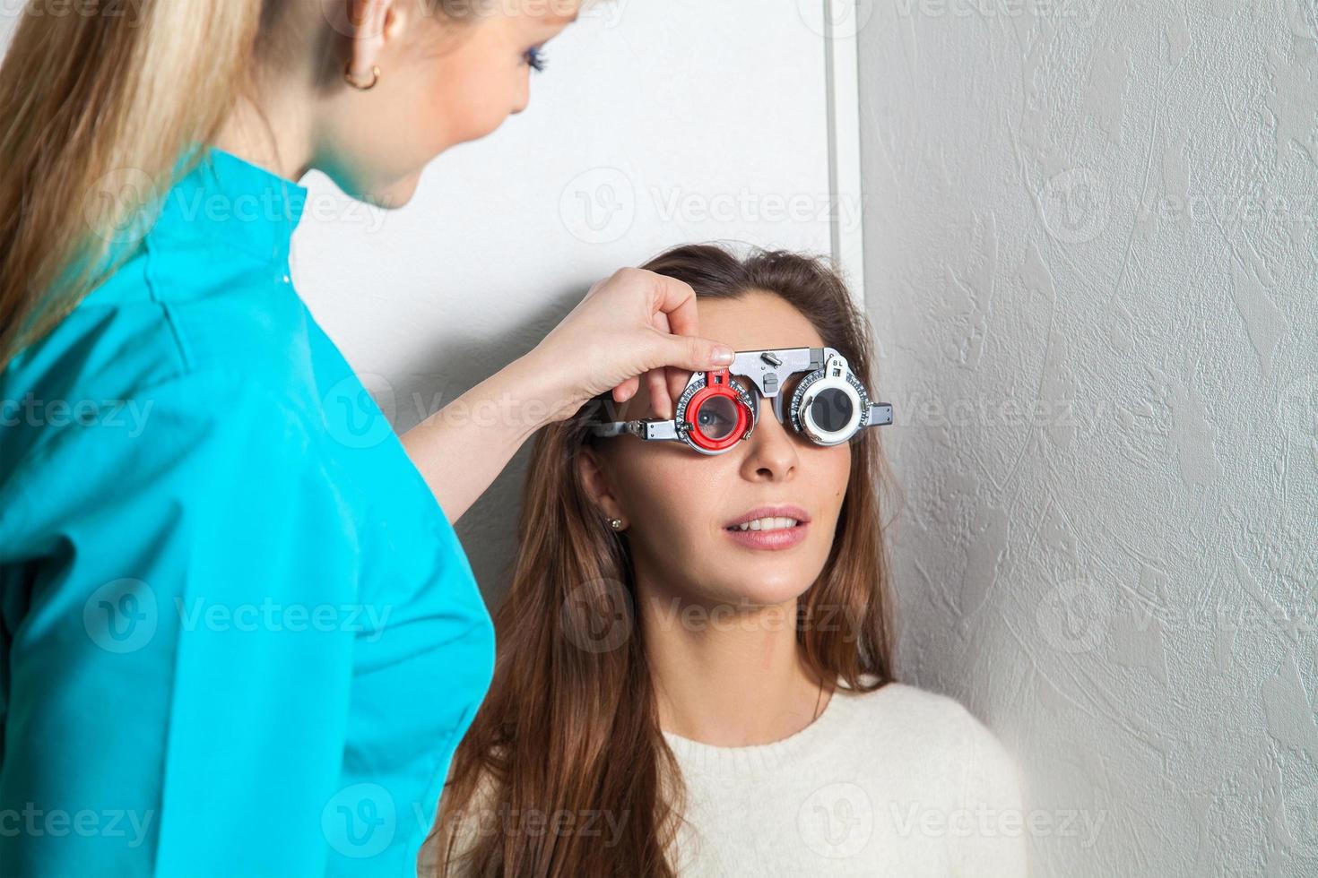 mujer adulta joven comprueba la visión en un oftalmólogo con lentes correctivos foto