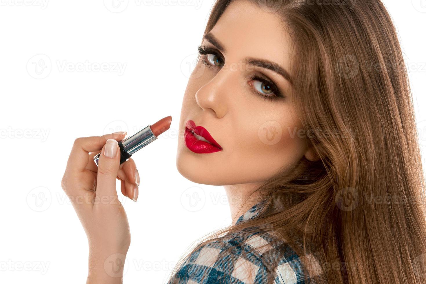 Close up portrait of young beautiful girl with lipstick in hand photo