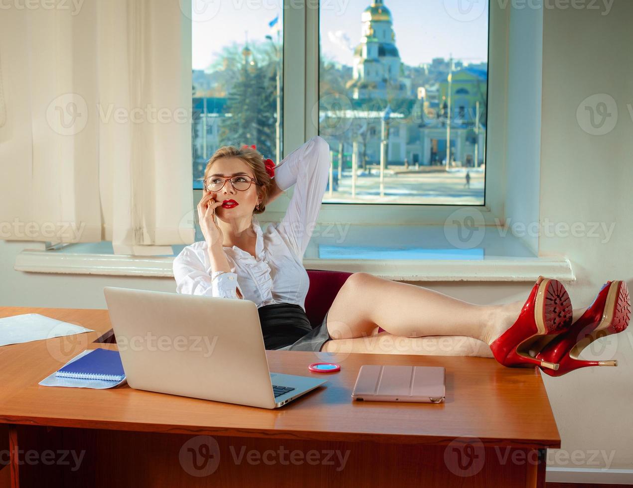 portrait of beautiful young secretary working from desk talking on cell phone photo