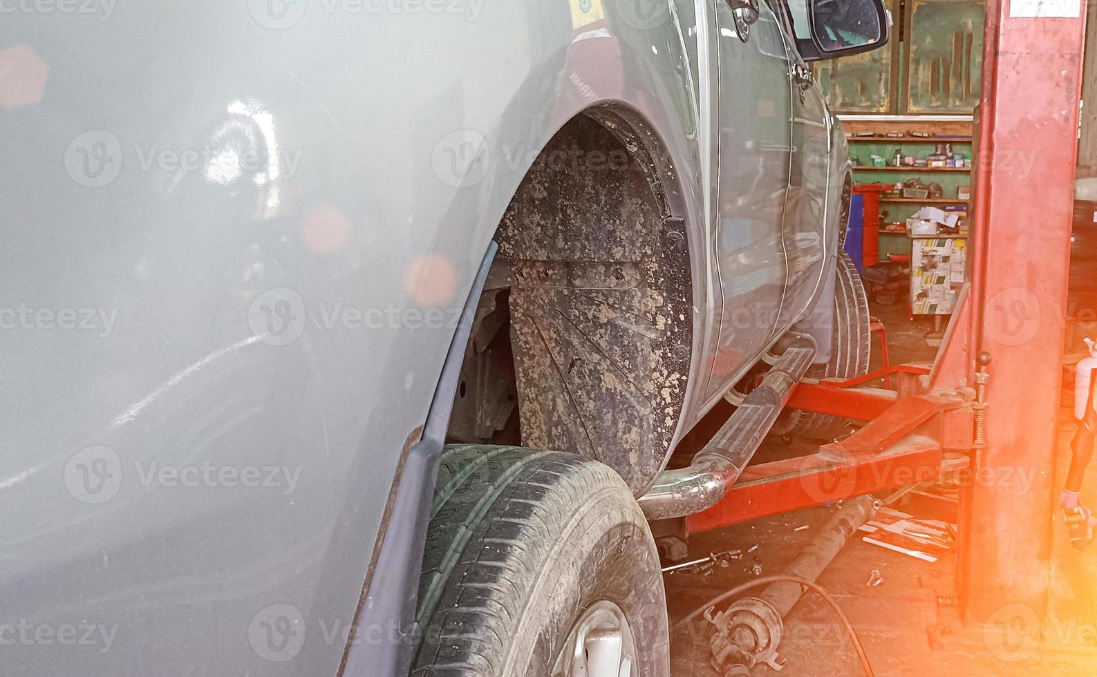 Side view of a car lifted off the ground by a large jack. photo