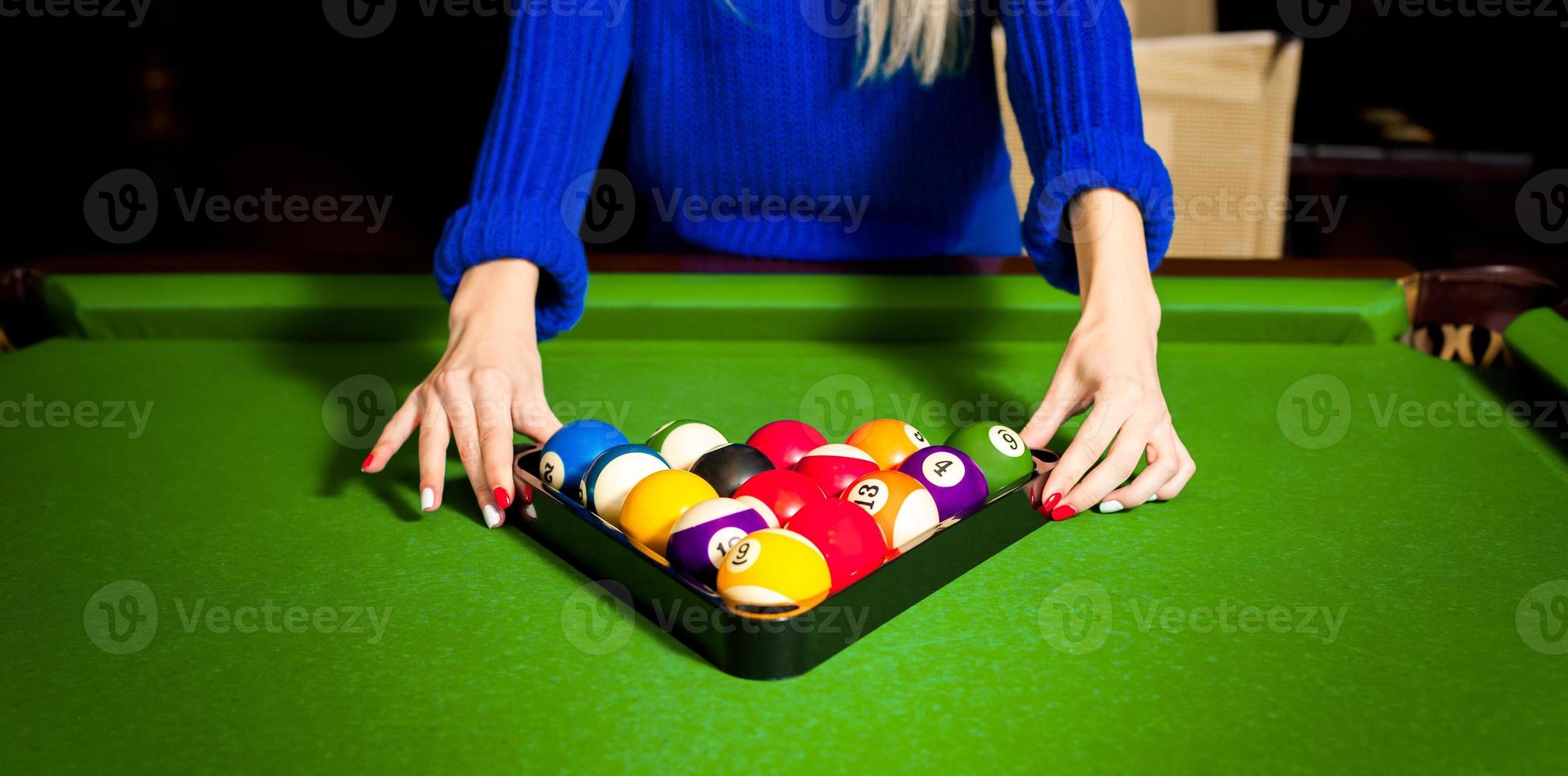 Woman puts a pyramid of balls for a pool on a billiard table photo