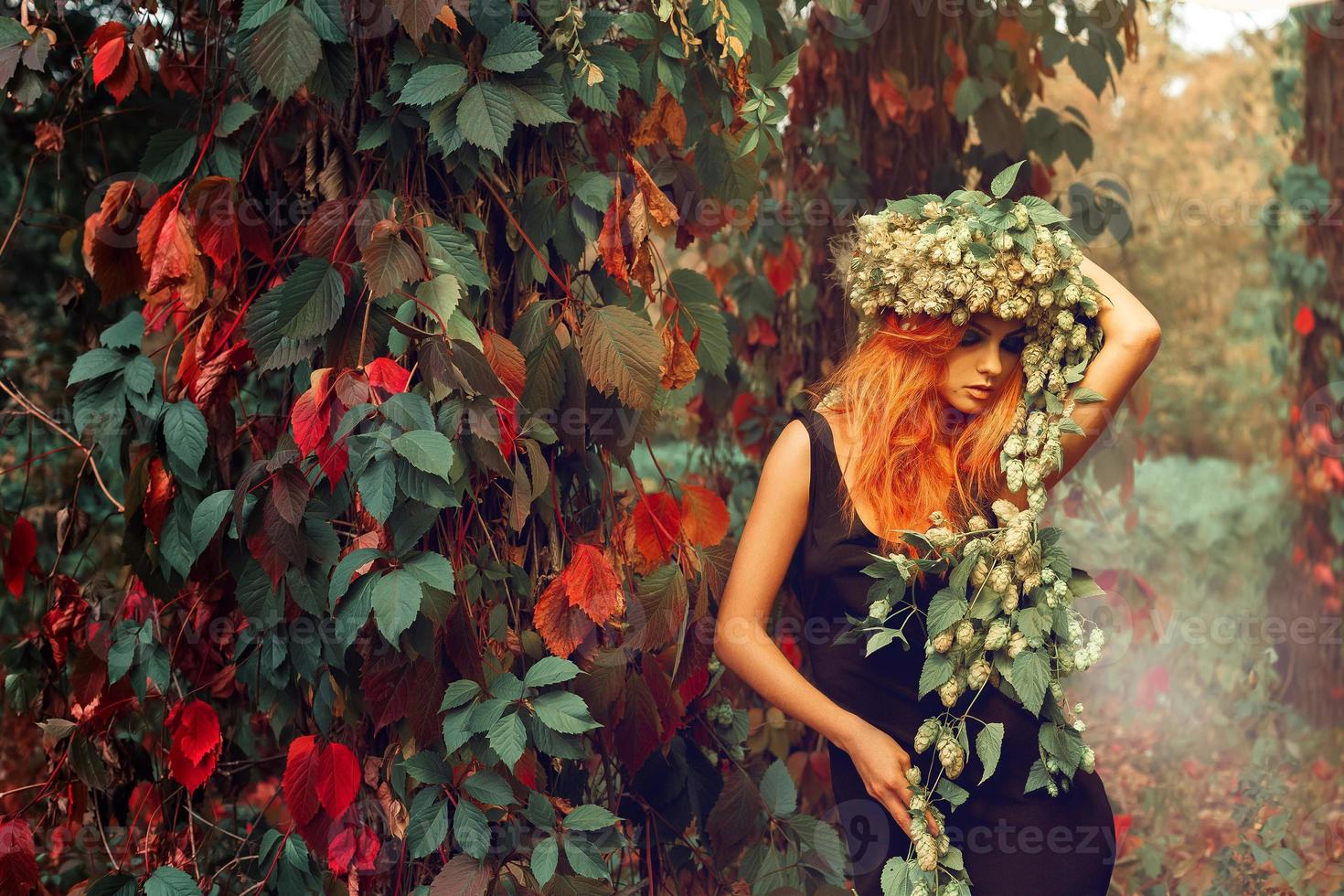 portrait of redhead young girl with wreath of hop on head outdoors photo