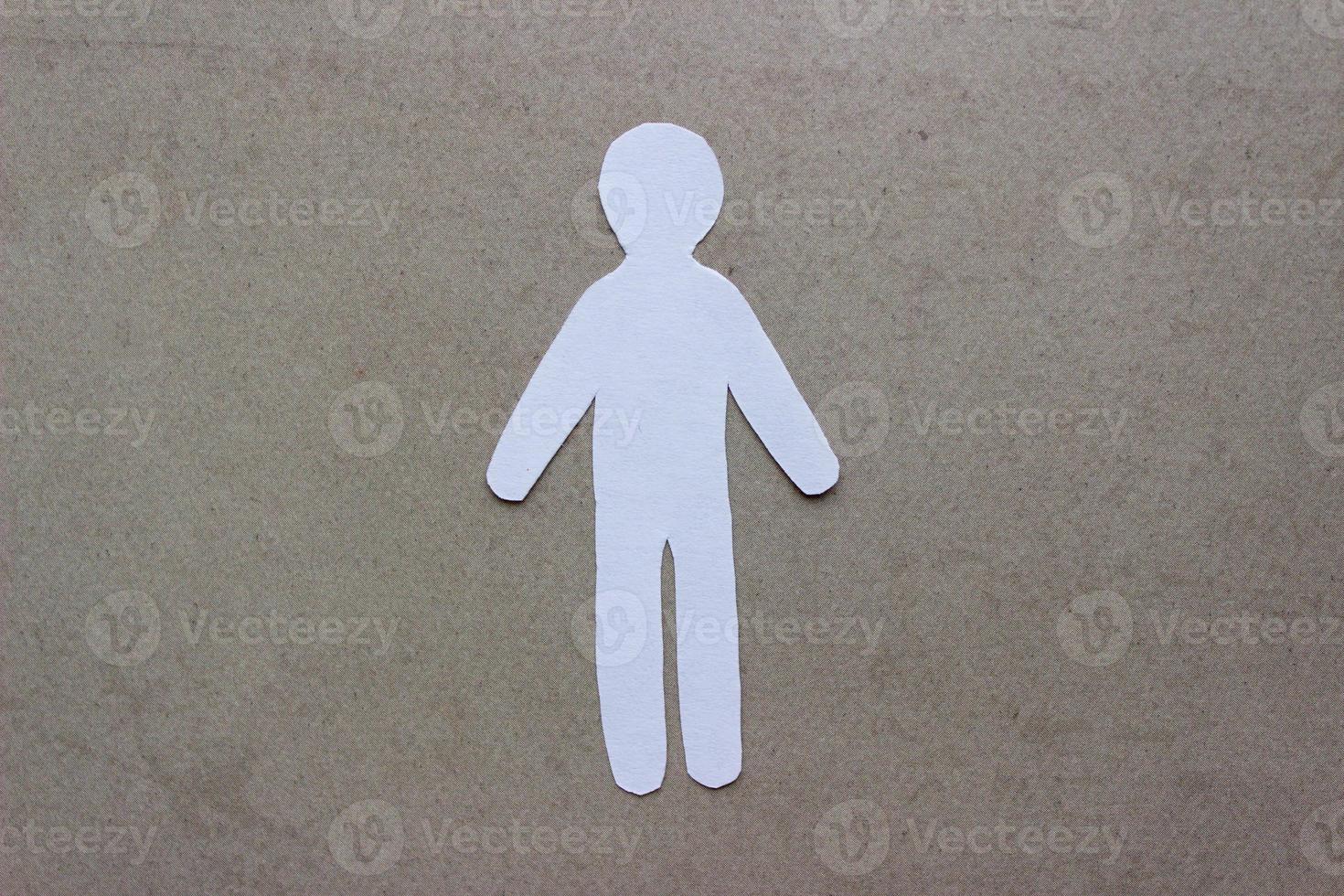 Silhouette of a man of white paper, cut by hand on beige background photo