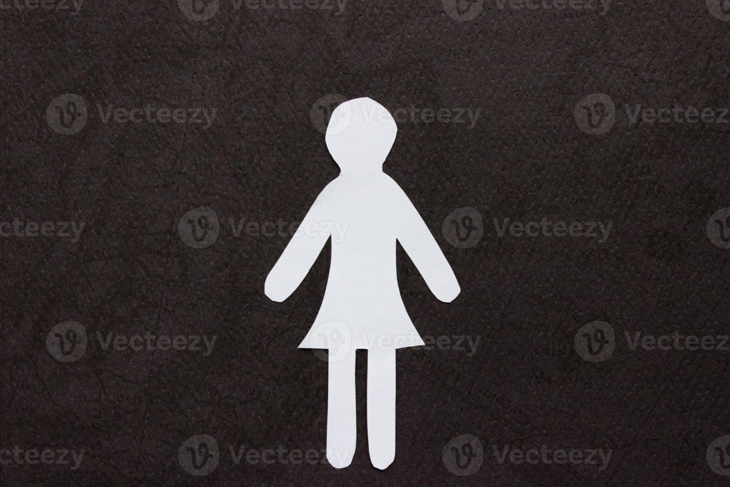 Silhouette of a woman in dress of white paper, cut by hand. In the center of photo on black background