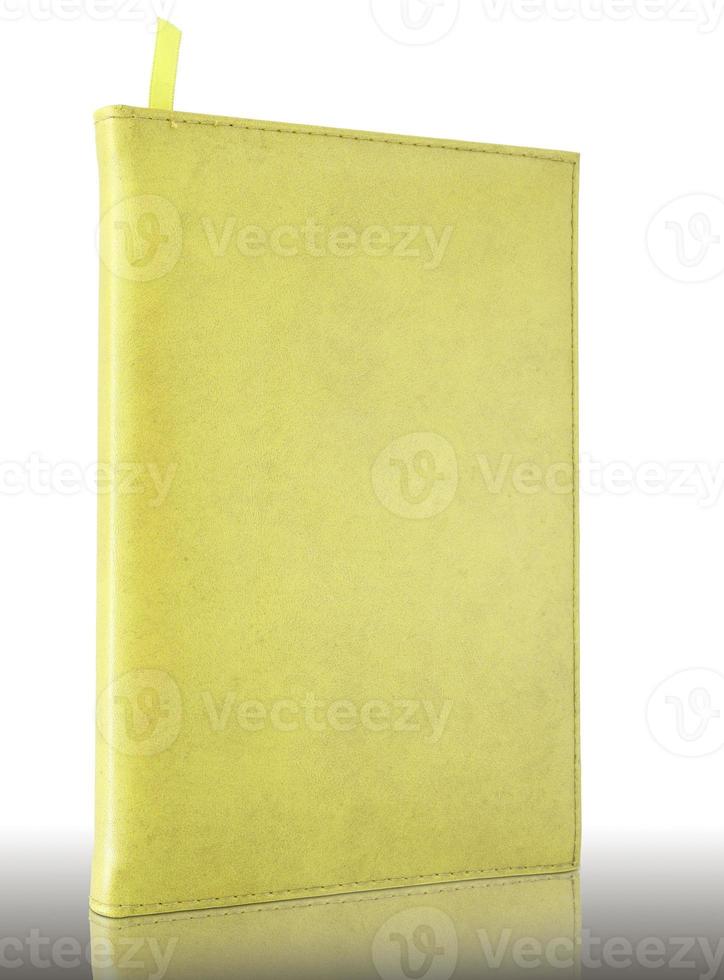 cuaderno de cuero amarillo sobre suelo reflectante y fondo blanco foto