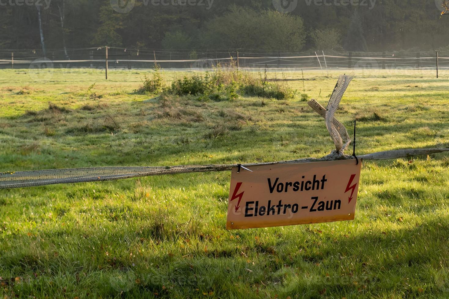 Meadow with warning sign caution electric fence photo