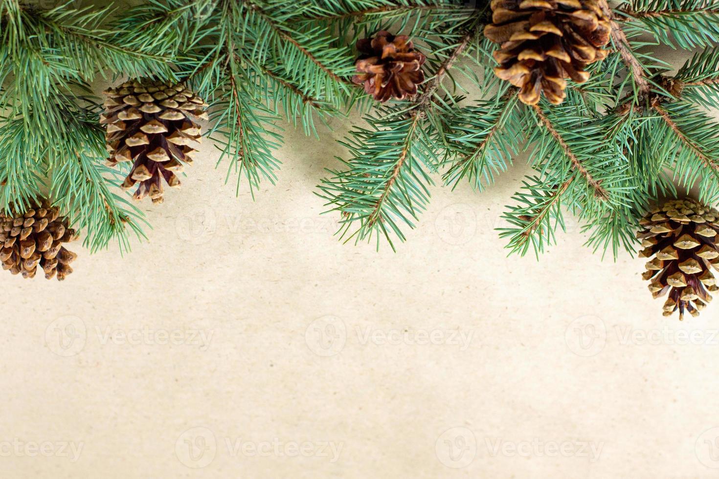 Border of fir tree branch with cones on craft paper for christmas card with copy space for text. Top view, flat lay photo