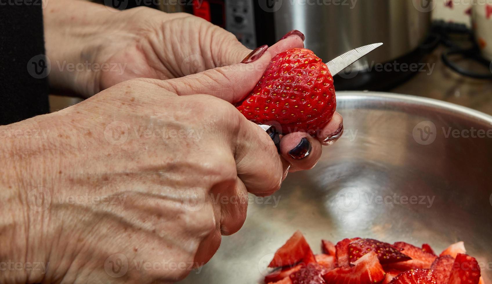 el chef corta fresas para el postre en la cocina de la casa foto