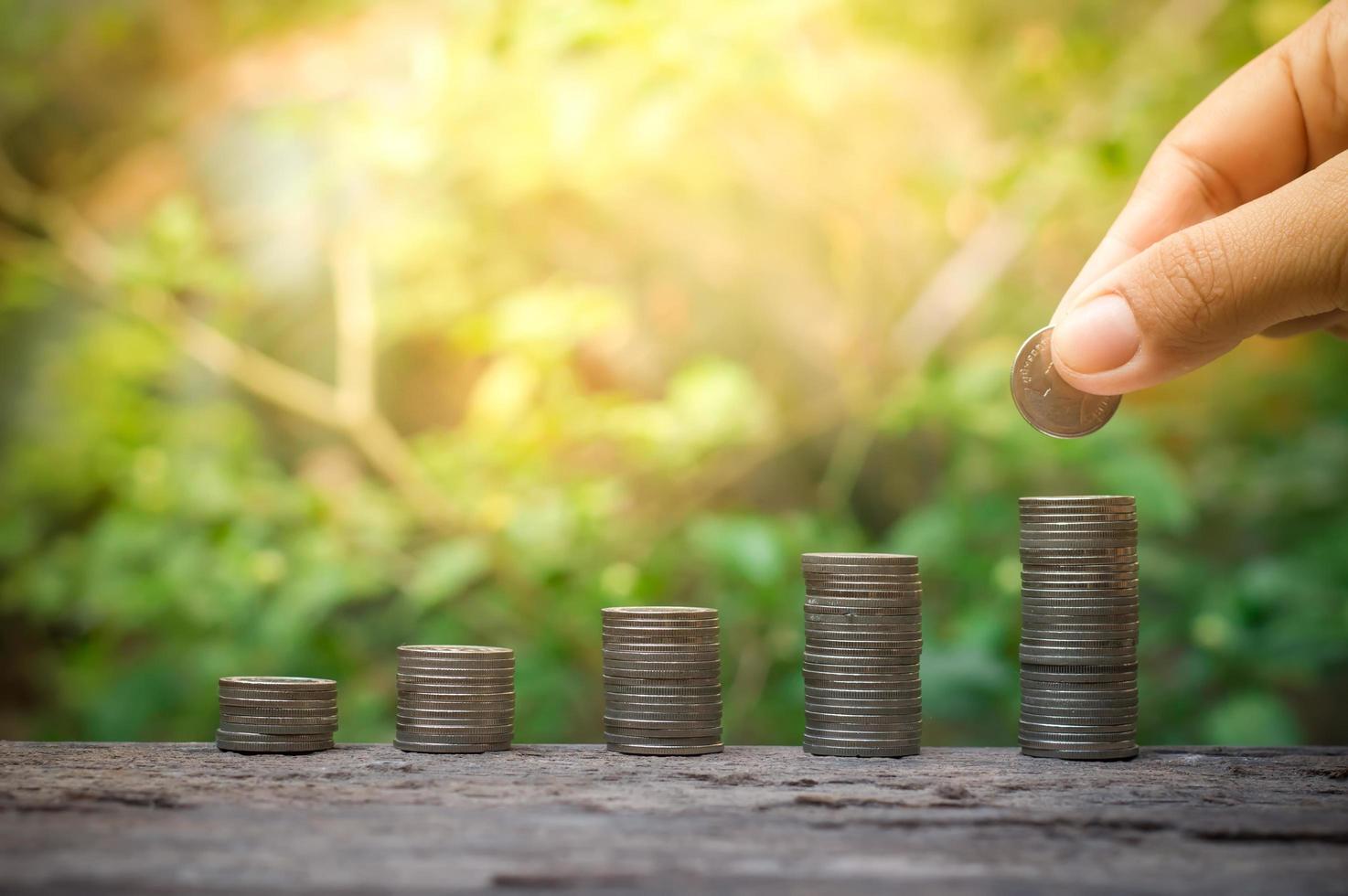 mano poniendo moneda en la pila de monedas para el concepto de ahorro foto