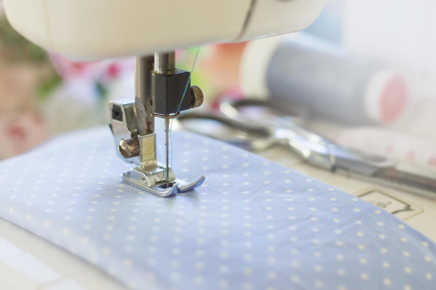 primer plano de la máquina de coser que trabaja con tela azul foto